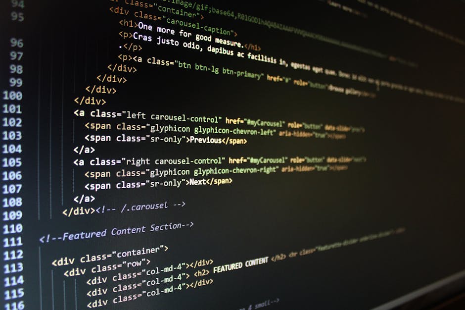 A person using a laptop placed on a wooden surface, with the screen displaying lines of code in a text editor. The individual's hand is resting on the keyboard, and they are wearing a wristwatch. The 